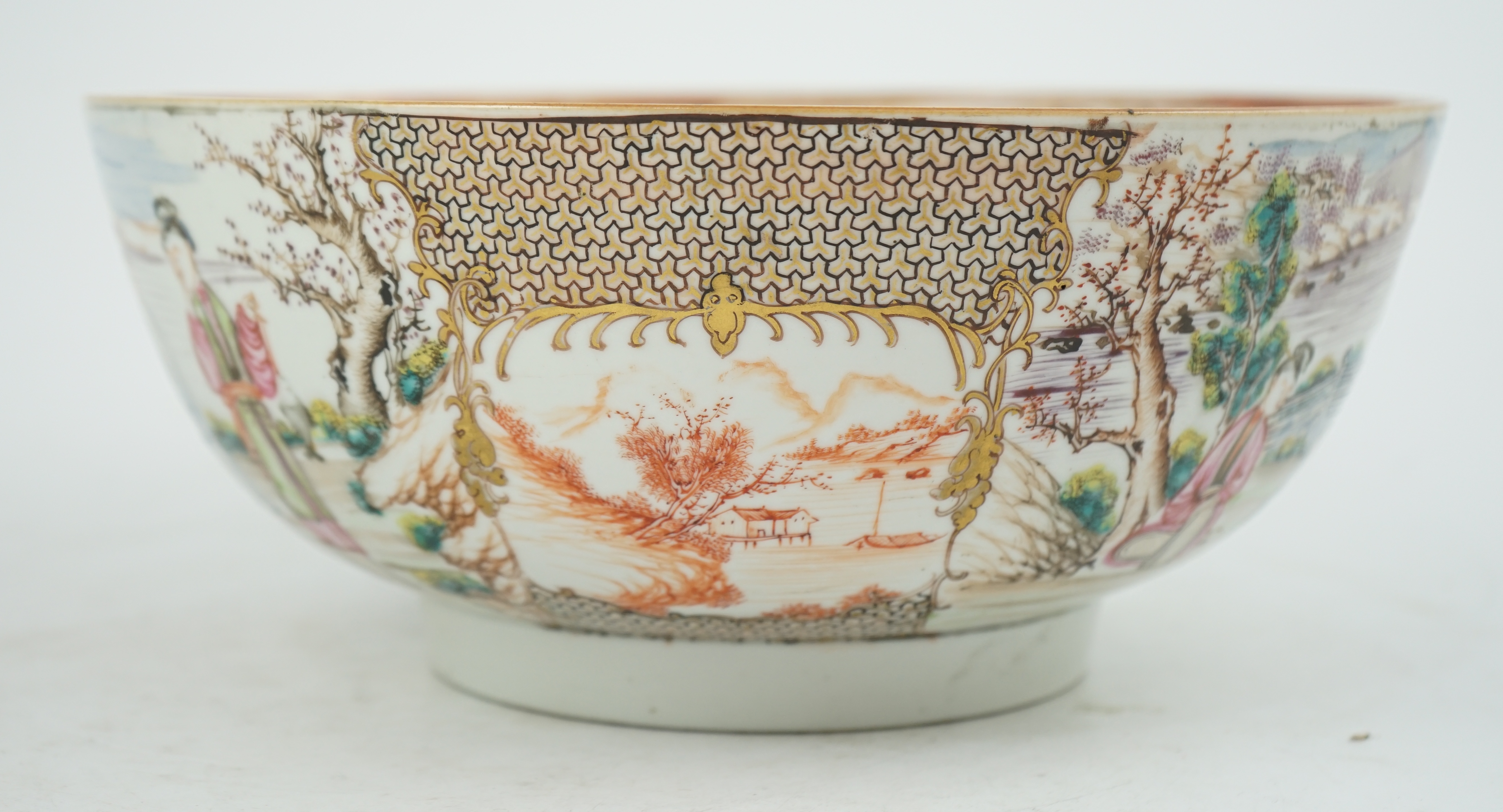 A Chinese famille rose ‘mandarin’ bowl, Qianlong period, painted with figures in a lakeside garden, between red enamelled landscape vignettes and cellular panels, 28.4cm diameter. Condition - there is a hairline crack to